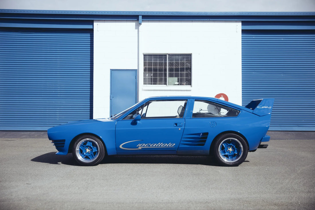 Powder blue Giocattolo Group B in side profile against blue roller doors.